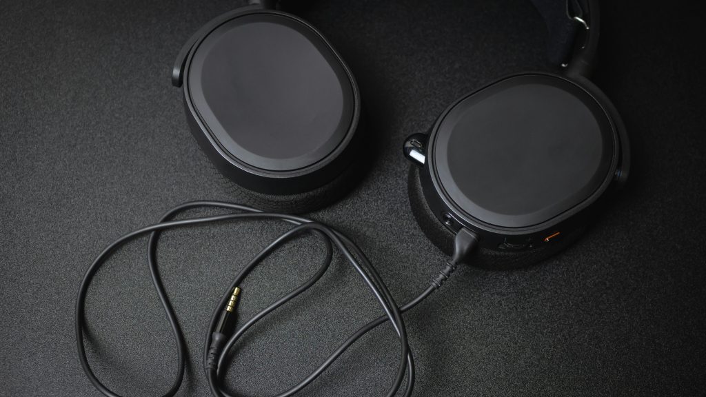 Close-up of a stylish black gaming headset with a detachable cable on a dark surface.